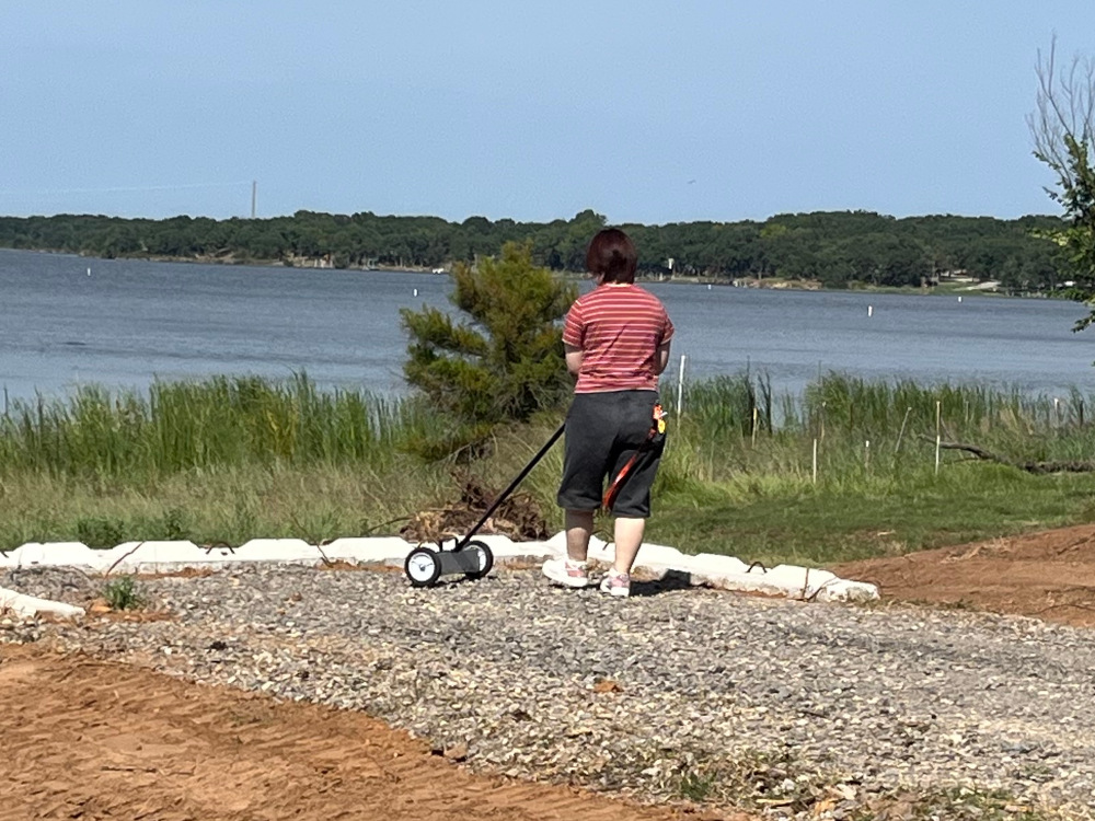 Student using a magnetic rake to pick up scrap metal.