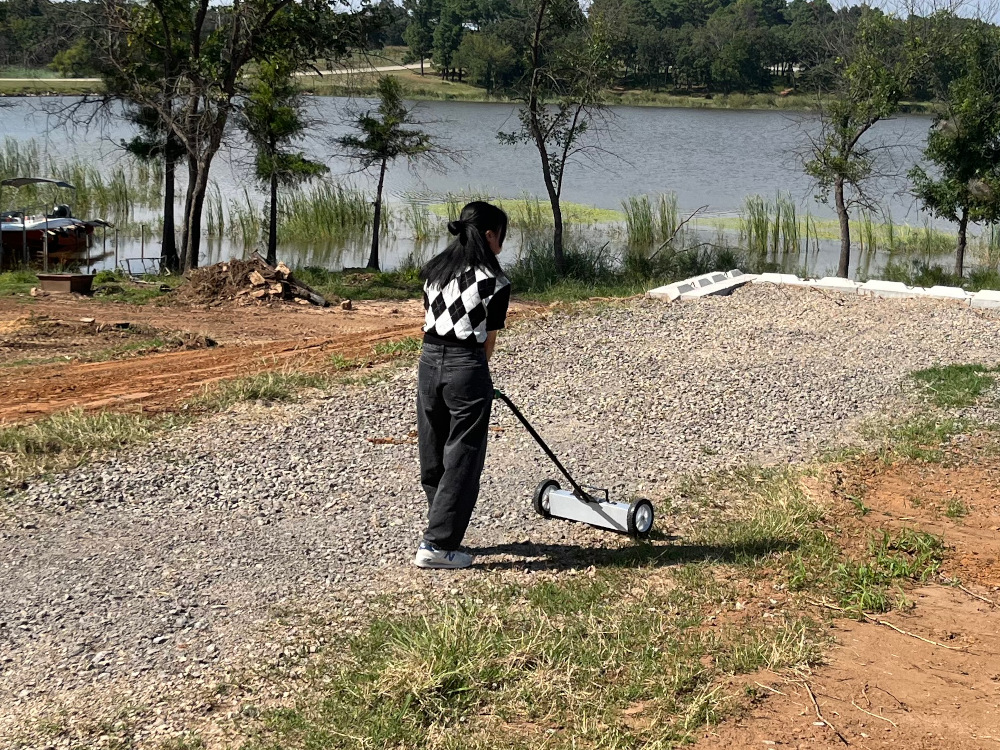 Student using a magnetic rake to pick up scrap metal.
